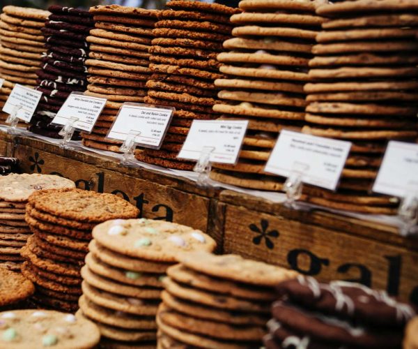 An enticing display of freshly baked cookies, arranged on rustic wooden shelves in a warmly lit cookies bakery.