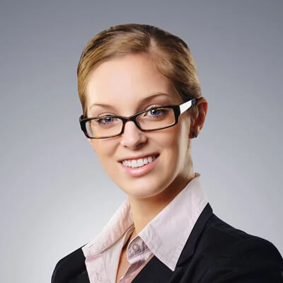 Image of a girl in her 30s with a white background wearing a women's suit and glasses