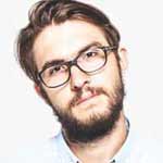 A person with a
                                brown beard and glasses is depicted with only his upper part visible, with a white background